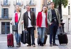 Les touristes positifs avec le bagage posent dehors Photographie stock libre de droits Les touristes positifs avec le bagage posent dehors Photographie stock libre de droits