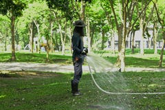 Les types arrosent la pelouse en parc photographie stock Les types arrosent la pelouse en parc photographie stock