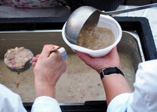 Les volontaires servent une soupe chaude dans un plat en plastique pour les pauvres et le sans-abri photographie stock Les volontaires servent une soupe chaude dans un plat en plastique pour les pauvres et le sans-abri photographie stock