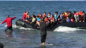 LESVOS, ГРЕЦИЯ - 2-ОЕ НОЯБРЯ 2015: Беженцы в резиновой шлюпке плавают для того чтобы подпирать от Турции LESVOS, ГРЕЦИЯ - 2-ОЕ НОЯБРЯ 2015: Беженцы в резиновой шлюпке плавают для того чтобы подпирать от Турции