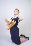 Leuk Kaukasisch pinupmeisje die uitstekende stipkleding dragen en baguettes op een witte achtergrond in de Studio houden stock afbeelding Leuk Kaukasisch pinupmeisje die uitstekende stipkleding dragen en baguettes op een witte achtergrond in de Studio houden stock afbeelding