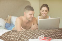 Leuk paar die laptop in bed met behulp van stock foto's Leuk paar die laptop in bed met behulp van stock foto's