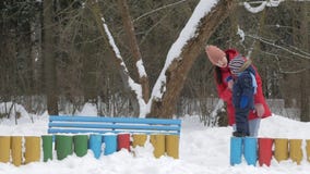 Leuk spelen weinig jongen en jonge moeder in de winter met sneeuw in het park Blauw jong geitje` s jasje en rood bij mamma stock footage Leuk spelen weinig jongen en jonge moeder in de winter met sneeuw in het park Blauw jong geitje` s jasje en rood bij mamma stock footage