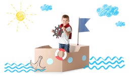 Leuk weinig jongen die met kartonschip spelen stock foto's Leuk weinig jongen die met kartonschip spelen stock foto's