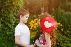 Leuk weinig jongen met gift rode ballons zijn vriendenmeisje stock afbeelding Leuk weinig jongen met gift rode ballons zijn vriendenmeisje stock afbeelding