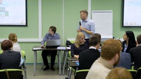 Leuke bedrijfsbus met microfoon die grafiek en diagrammen op de projectieschermen tonen in het publiek stock videobeelden Leuke bedrijfsbus met microfoon die grafiek en diagrammen op de projectieschermen tonen in het publiek stock videobeelden