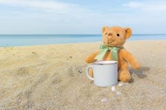 Leuke bruine teddybeerzitting op het strand met een koffiekop Concept voor ontspanning, comfort en vakantie met exemplaarruimte stock fotografie Leuke bruine teddybeerzitting op het strand met een koffiekop Concept voor ontspanning, comfort en vakantie met exemplaarruimte stock fotografie
