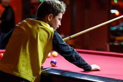 Leuke jongen in het gele biljart van t-shirtspelen of pool in club Het jonge Jonge geitje leert om snooker te spelen Jongen met b stock afbeeldingen Leuke jongen in het gele biljart van t-shirtspelen of pool in club Het jonge Jonge geitje leert om snooker te spelen Jongen met b stock afbeeldingen