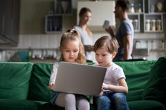Leuke van de kinderenzuster en broer holdingslaptop die online op letten stock afbeelding Leuke van de kinderenzuster en broer holdingslaptop die online op letten stock afbeelding