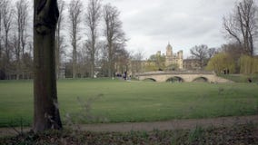 Leute stochern auf Fluss-Nocken, Brücke und historischem Gebäude im Hintergrund stock footage Leute stochern auf Fluss-Nocken, Brücke und historischem Gebäude im Hintergrund stock footage