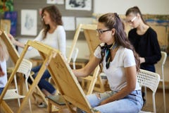 Lezione di disegno nello studio di arte Le ragazze incantanti dell'albero dipingono le immagini che si siedono ai cavalletti fotografie stock libere da diritti Lezione di disegno nello studio di arte Le ragazze incantanti dell'albero dipingono le immagini che si siedono ai cavalletti fotografie stock libere da diritti