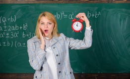 Leçon expérimentée de début d'éducateur Elle s'inquiète de la discipline Quelle heure est il Réveil de prise de professeur de fem image stock Leçon expérimentée de début d'éducateur Elle s'inquiète de la discipline Quelle heure est il Réveil de prise de professeur de fem image stock