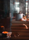 Libri impilati e tè caldo contro la finestra piovosa fotografie stock libere da diritti Libri impilati e tè caldo contro la finestra piovosa fotografie stock libere da diritti