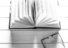 Libro abierto listo para leer mentiras en una tabla de madera blanca al lado de los vidrios redondos viejos foto de archivo libre de regalías Libro abierto listo para leer mentiras en una tabla de madera blanca al lado de los vidrios redondos viejos foto de archivo libre de regalías