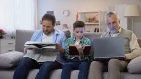 Libro de lectura del papá y del hijo y periódico, ordenador portátil de envejecimiento de la tenencia del hombre, generaciones almacen de metraje de vídeo Libro de lectura del papá y del hijo y periódico, ordenador portátil de envejecimiento de la tenencia del hombre, generaciones almacen de metraje de vídeo