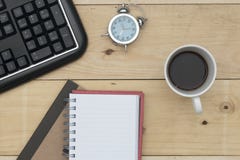 Lieu de travail avec le clavier, le réveil, le café et le carnet sur la table en bois images stock Lieu de travail avec le clavier, le réveil, le café et le carnet sur la table en bois images stock
