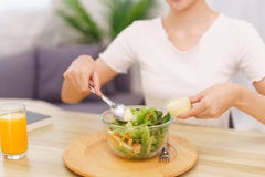 Lifestyle In Living Room Concept, Asian Woman Using Spoon To Ladle Salad Dressing Into Salad Bowl Stock Image