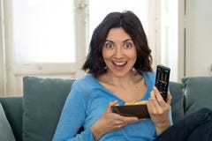 Lifestyle portrait of cheerful young woman sitting on the couch watching TV holding remote control royalty free stock image Lifestyle portrait of cheerful young woman sitting on the couch watching TV holding remote control royalty free stock image