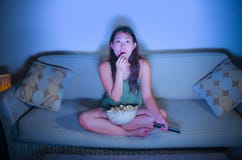 Lifestyle Portrait Of Young Sweet And Surprised Asian Korean Woman Watching Television Suspense Movie Or News Looking Shocked And Royalty Free Stock Photo