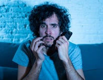 Picture of young man looking disgusted sitting on sofa watching violent movie on TV at night royalty free stock image Picture of young man looking disgusted sitting on sofa watching violent movie on TV at night royalty free stock image