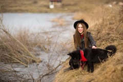 Lifestyle portrait of young woman in black hat with her dog, resting by the lake on a nice and warm autumn day royalty free stock photography Lifestyle portrait of young woman in black hat with her dog, resting by the lake on a nice and warm autumn day royalty free stock photography