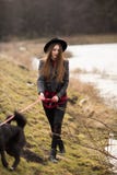 Lifestyle portrait of young woman in black hat with her dog, walking by the lake on a nice and warm autumn day stock image Lifestyle portrait of young woman in black hat with her dog, walking by the lake on a nice and warm autumn day stock image