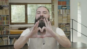 Ligando la reacción de un hombre atractivo joven con la barba que hace un corazón forme usando sus manos y fingeres - metrajes Ligando la reacción de un hombre atractivo joven con la barba que hace un corazón forme usando sus manos y fingeres - metrajes