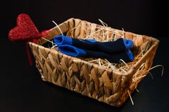 Liggen het de baby blauwe sokken en hart in een mand op het hooi, op een zwarte achtergrond royalty-vrije stock afbeeldingen Liggen het de baby blauwe sokken en hart in een mand op het hooi, op een zwarte achtergrond royalty-vrije stock afbeeldingen