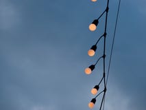 Light bulbs hanging on a electricity wire in cloudy sky background stock photo Light bulbs hanging on a electricity wire in cloudy sky background stock photo