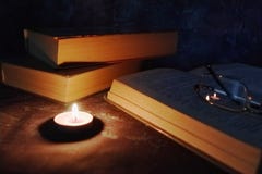 Lighted candles in an intimate setting, old books, yellowed from time to time, glasses in a knitted yellow thread royalty free stock photo Lighted candles in an intimate setting, old books, yellowed from time to time, glasses in a knitted yellow thread royalty free stock photo