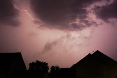 Lightening bolt over houses in the middle of a storm