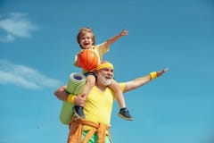 Like sports. Joyful old-aged man and cute little boy practicing sport and healthy lifestyle over sky background. Fathers