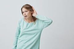 Linguagem corporal A mulher loura caucasiano entusiasmado nova com cabelo longo na camiseta azul que olha a câmera abriu a boca Imagens de Stock Linguagem corporal A mulher loura caucasiano entusiasmado nova com cabelo longo na camiseta azul que olha a câmera abriu a boca Imagens de Stock