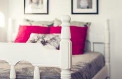 Lit découpé en bois blanc avec le couvre-lit gris et les oreillers rouges photographie stock libre de droits Lit découpé en bois blanc avec le couvre-lit gris et les oreillers rouges photographie stock libre de droits