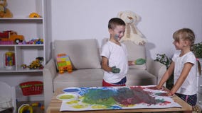 Lite gulliga lyckliga roliga handprints för barnmålningfärg på det vita arket av papper lager videofilmer Lite gulliga lyckliga roliga handprints för barnmålningfärg på det vita arket av papper lager videofilmer