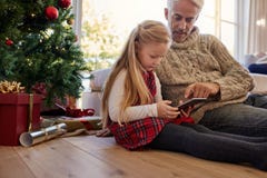 Liten flicka med farfarsammanträde, genom trädet och att använda för jul royaltyfri foto Liten flicka med farfarsammanträde, genom trädet och att använda för jul royaltyfri foto