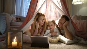 Liten flicka och henne föräldrar som tycker om hålla ögonen på tecknade filmer direktanslutet i tältet i barnkammaren lager videofilmer Liten flicka och henne föräldrar som tycker om hålla ögonen på tecknade filmer direktanslutet i tältet i barnkammaren lager videofilmer