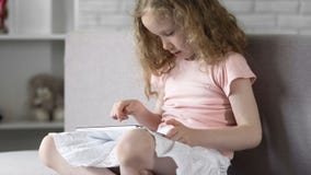 Liten flicka som använder minnestavlan för att spela lekar, modern utveckling, grejböjelse arkivfoto Liten flicka som använder minnestavlan för att spela lekar, modern utveckling, grejböjelse arkivfoto