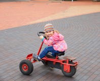 Liten flicka som har gyckel som kör en pedal- bil i dag royaltyfria foton Liten flicka som har gyckel som kör en pedal- bil i dag royaltyfria foton