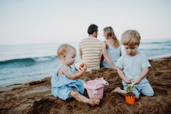 Litet barnbarn med f?r?ldrar som spelar p? sandstranden p? sommarferie arkivfoto Litet barnbarn med f?r?ldrar som spelar p? sandstranden p? sommarferie arkivfoto
