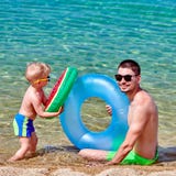 Litet barnpojke på stranden med fadern arkivfoto Litet barnpojke på stranden med fadern arkivfoto