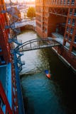 Litet fartyg under bron över kanalen mellan byggnader för röd tegelsten i det gamla lagerområdet Speicherstadt i Hamburg in royaltyfri bild Litet fartyg under bron över kanalen mellan byggnader för röd tegelsten i det gamla lagerområdet Speicherstadt i Hamburg in royaltyfri bild