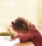 Little Adorable Girl Writing Her Homework In Exercise Book. Stock Image