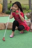 little girl playing mini golf
