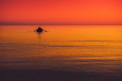 little boat in a sea red orange sky at sunset