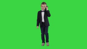 Little boy in a costume making a phone call while walking on a green screen, chroma key.