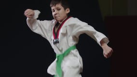 A little boy doing martial arts - jumping on the spot and showing a kick from the turn