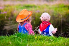 Little boy and girl dressed up as cowboy and cowgirl playing wit royalty free stock image Little boy and girl dressed up as cowboy and cowgirl playing wit royalty free stock image
