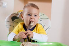 The little boy is holding a fork and eats itself stock image The little boy is holding a fork and eats itself stock image