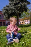 Little boy playing with grass and toy police car in nature